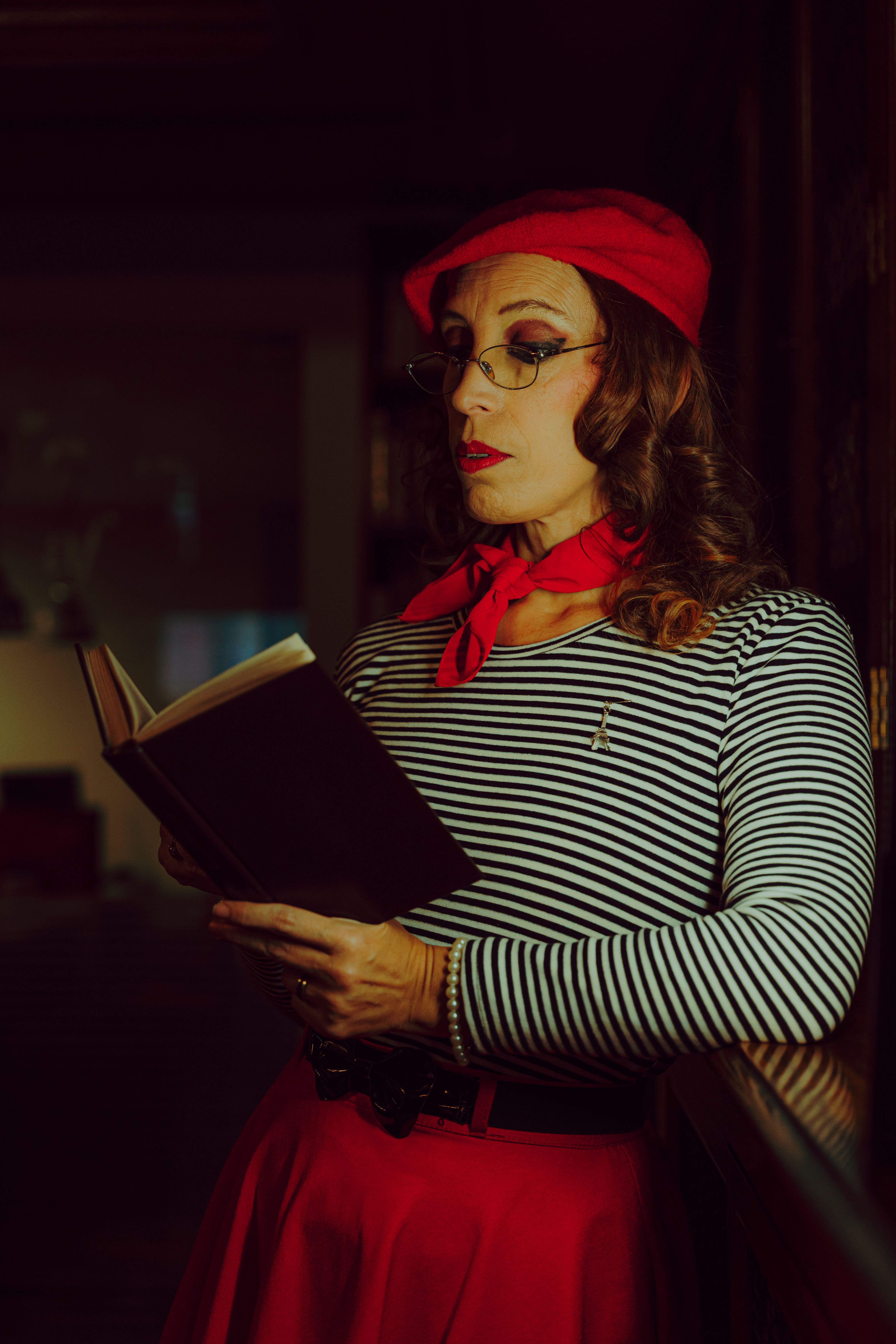 grátis Uma mulher com uma roupa de inspiração francesa lê um livro em um ambiente fechado, exalando elegância e estilo. Foto profissional