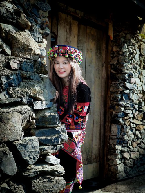 Free Woman in cultural attire near rustic stone walls outdoors. Stock Photo