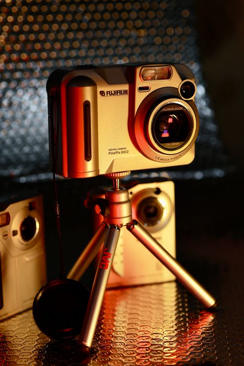 Free Retro Fujifilm instant camera on tripod with warm, moody lighting. Ideal for nostalgia and vintage themes. Stock Photo