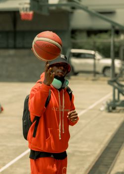 Young athlete spins a basketball on finger, showcasing skill and balance in an urban sports setting.