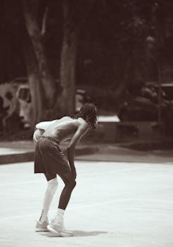 A focused athlete takes a break during an intense street basketball session at night.