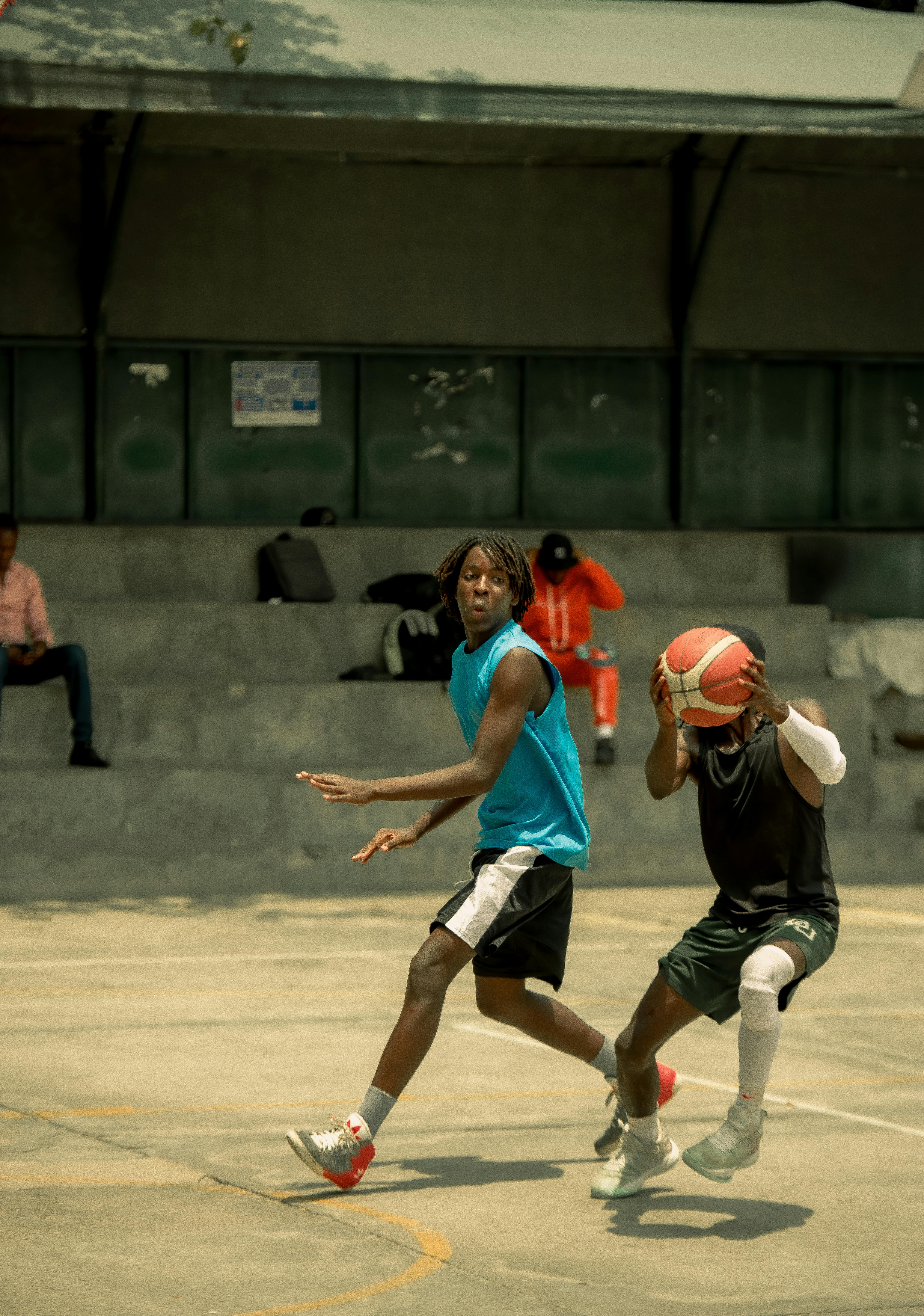 Two young men playing basketball on an outdoor court in a lively and dynamic setting.