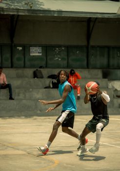 Two young men playing basketball on an outdoor court in a lively and dynamic setting.