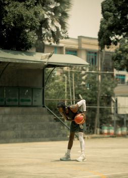 Young adult playing basketball on an outdoor court, showcasing skill and agility.