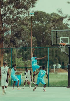 Energetic youth basketball game in outdoor court, vibrant team action on a sunny day.