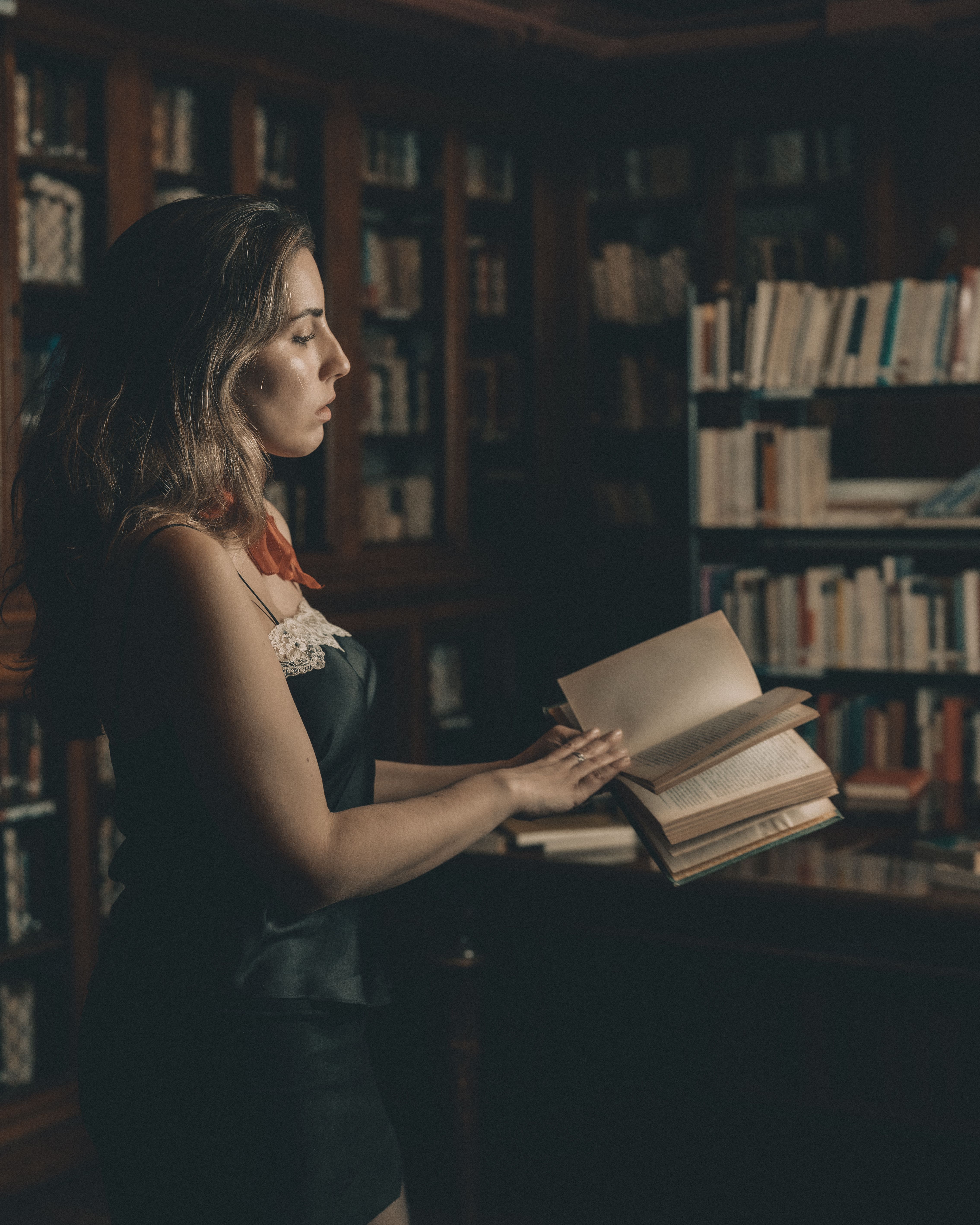 Woman Reading in Atmospheric Library Setting · Free Stock Photo