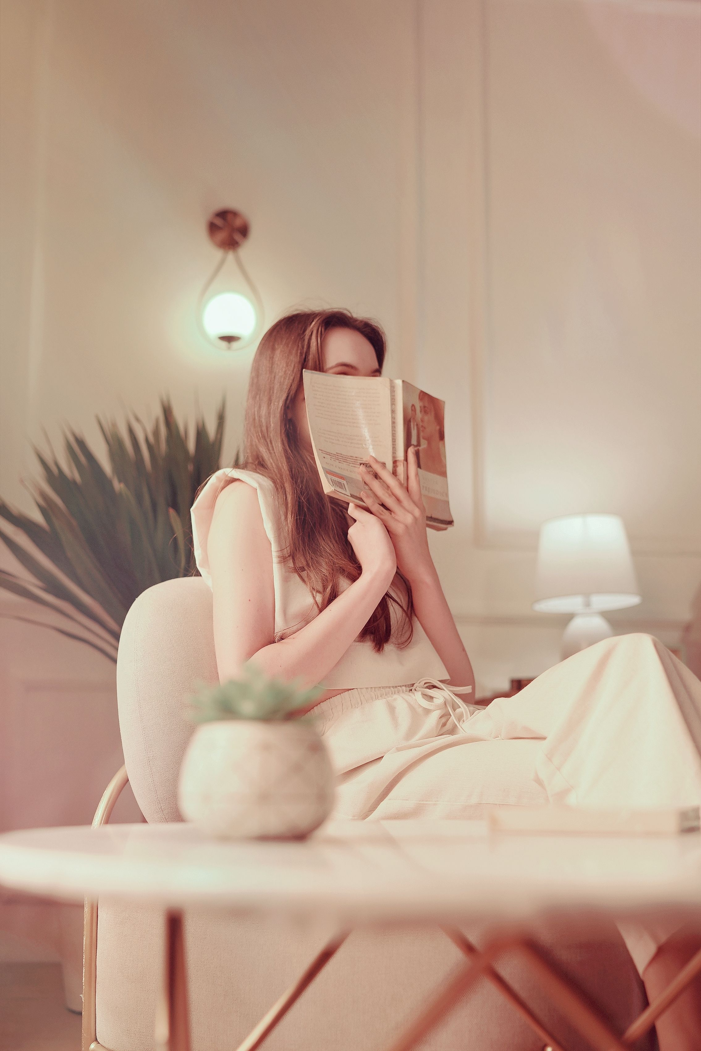 A woman enjoys a book in a cozy, elegantly lit indoor setting.