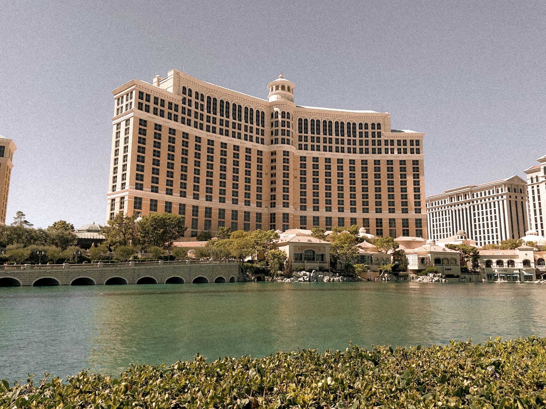A view of the iconic Bellagio Hotel in Las Vegas with clear skies and reflection in the water.