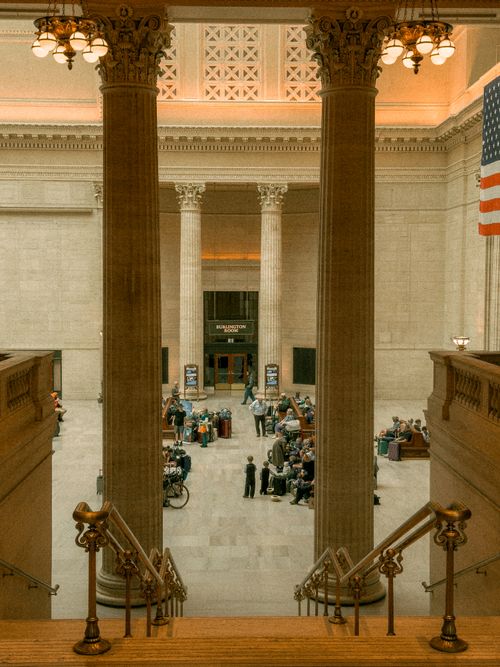 Free Elegant indoor hall with columns, flag, and people gathered for an event. Stock Photo