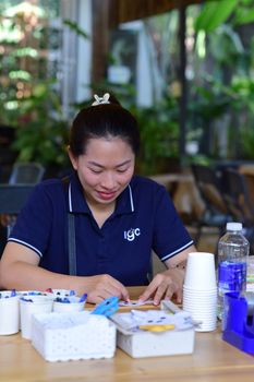 A woman attentively creating crafts indoors amidst a cozy and creative environment.