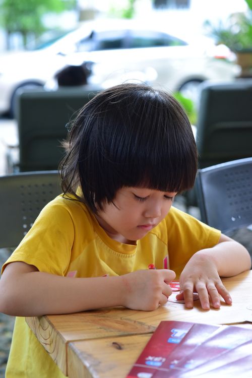 Free Young child deeply engaged in drawing at an outdoor table, showcasing concentration and creativity. Stock Photo