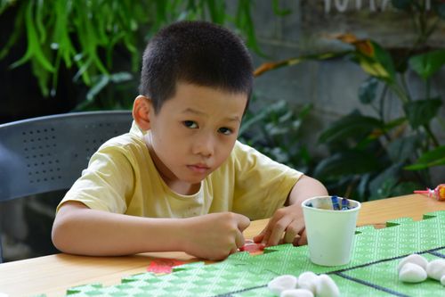 Free A young child engaged in art and crafts outdoors, focused on creativity and fun. Stock Photo