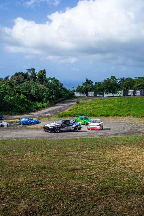 Free Dynamic image of cars racing on an outdoor dirt track amidst lush greenery. Stock Photo