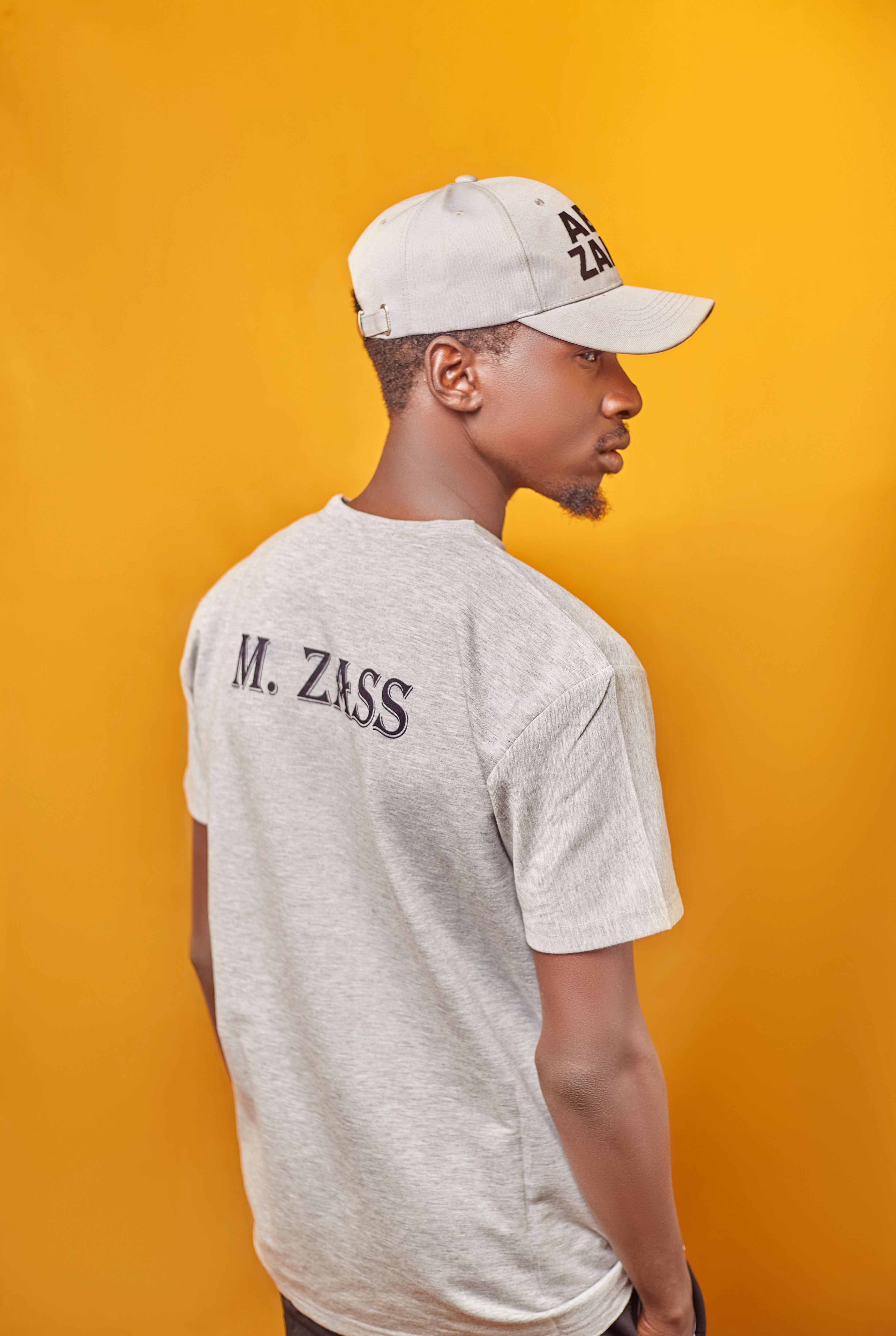 Portrait of a stylish African American man wearing branded casual wear against a bold orange background.