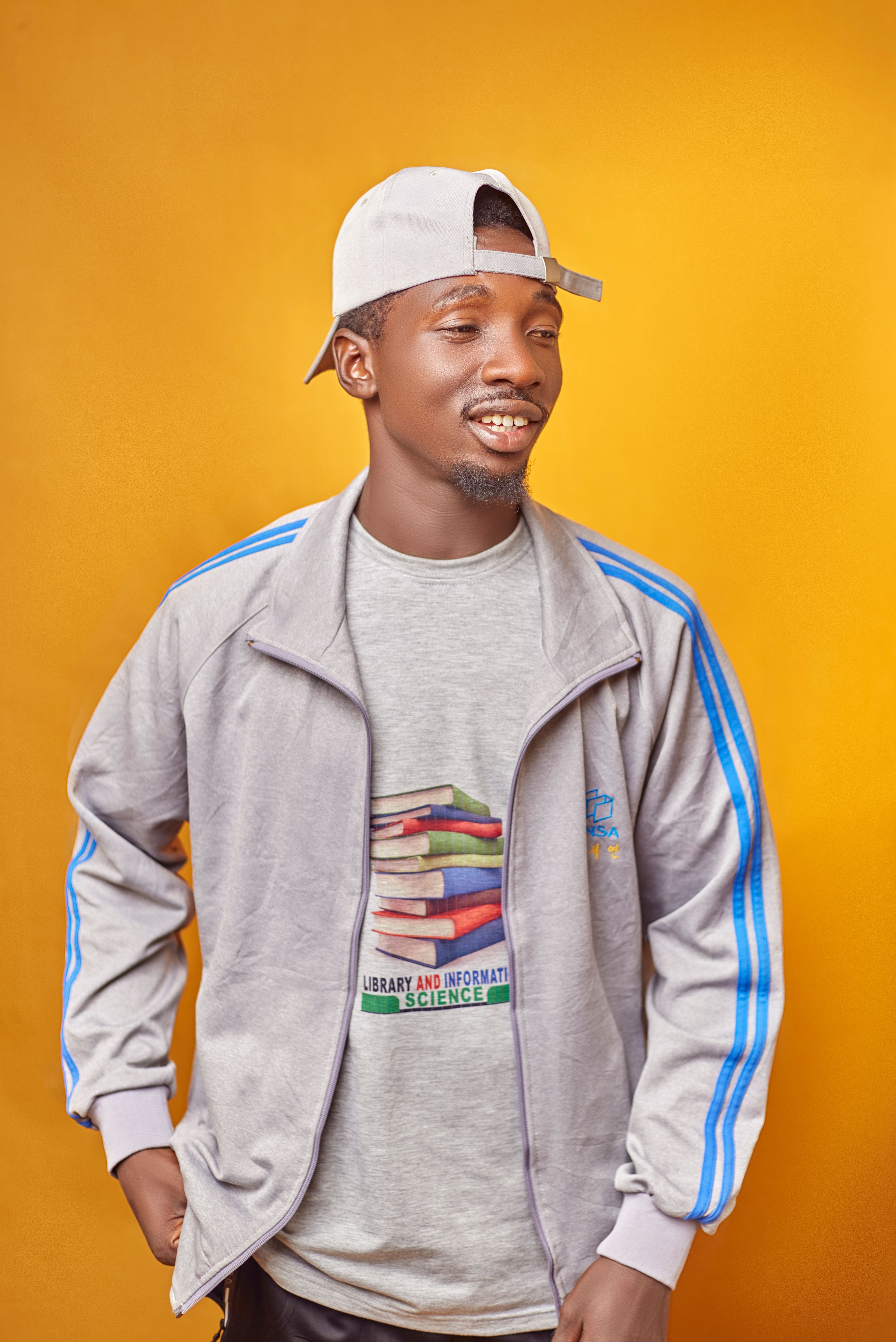 Young man wearing gray jacket and cap with a bright orange backdrop. Casual style.