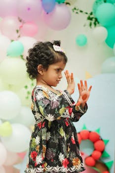A child joyfully engages at a colorful birthday party with pastel balloons and festive decor indoors.