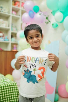 Adorable child celebrating a dinosaur-themed third birthday party indoors with balloons.