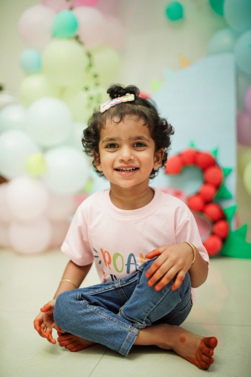 Free Smiling child at a dinosaur-themed birthday celebration with balloons and a colorful setup. Stock Photo