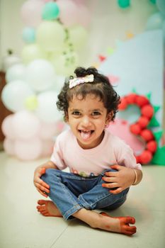 Adorable toddler enjoying a birthday party with colorful balloons and playful dinosaur theme.