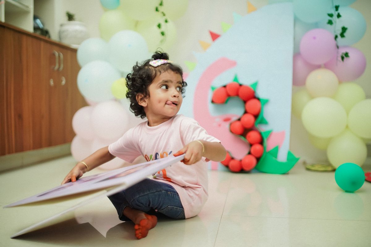 Cute child enjoys a fun dinosaur-themed birthday with balloons and decorations. Stock Photo.