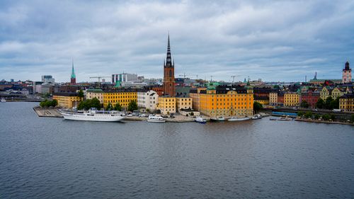 Free A panoramic view of Stockholm's historic waterfront with colorful buildings and boats, under a cloudy sky. Stock Photo