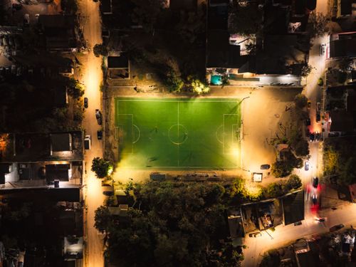 Free Aerial image of a brightly lit soccer field surrounded by urban lights at night. Stock Photo