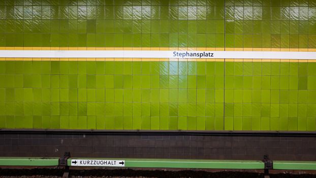 Vibrant green tiled wall at Stephansplatz subway station in Hamburg, Germany.