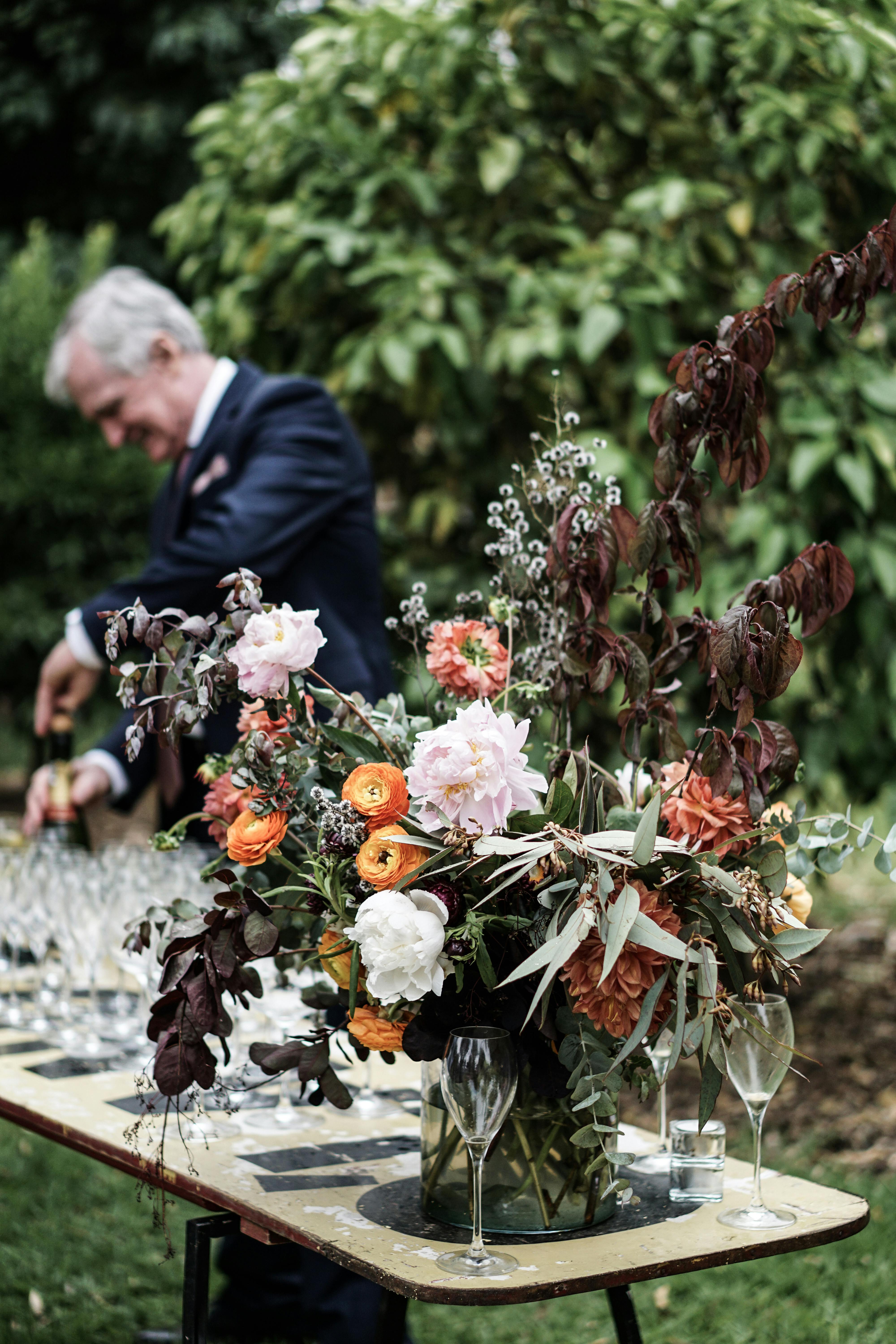 桌子上花卉布置得郁郁葱葱，男人在花园里供应饮料