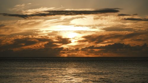 Free Captivating ocean sunset with fiery orange clouds and calming waves. Stock Photo
