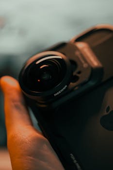 Detailed shot of a smartphone with an attached fisheye lens, showcasing modern mobile photography equipment.