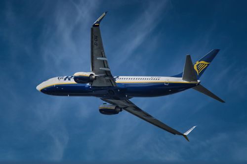 Free A commercial jet airliner soaring through a clear blue sky, showcasing flight and travel. Stock Photo