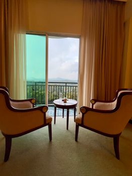 Two elegant chairs face a scenic balcony view, creating a cozy indoor ambiance.