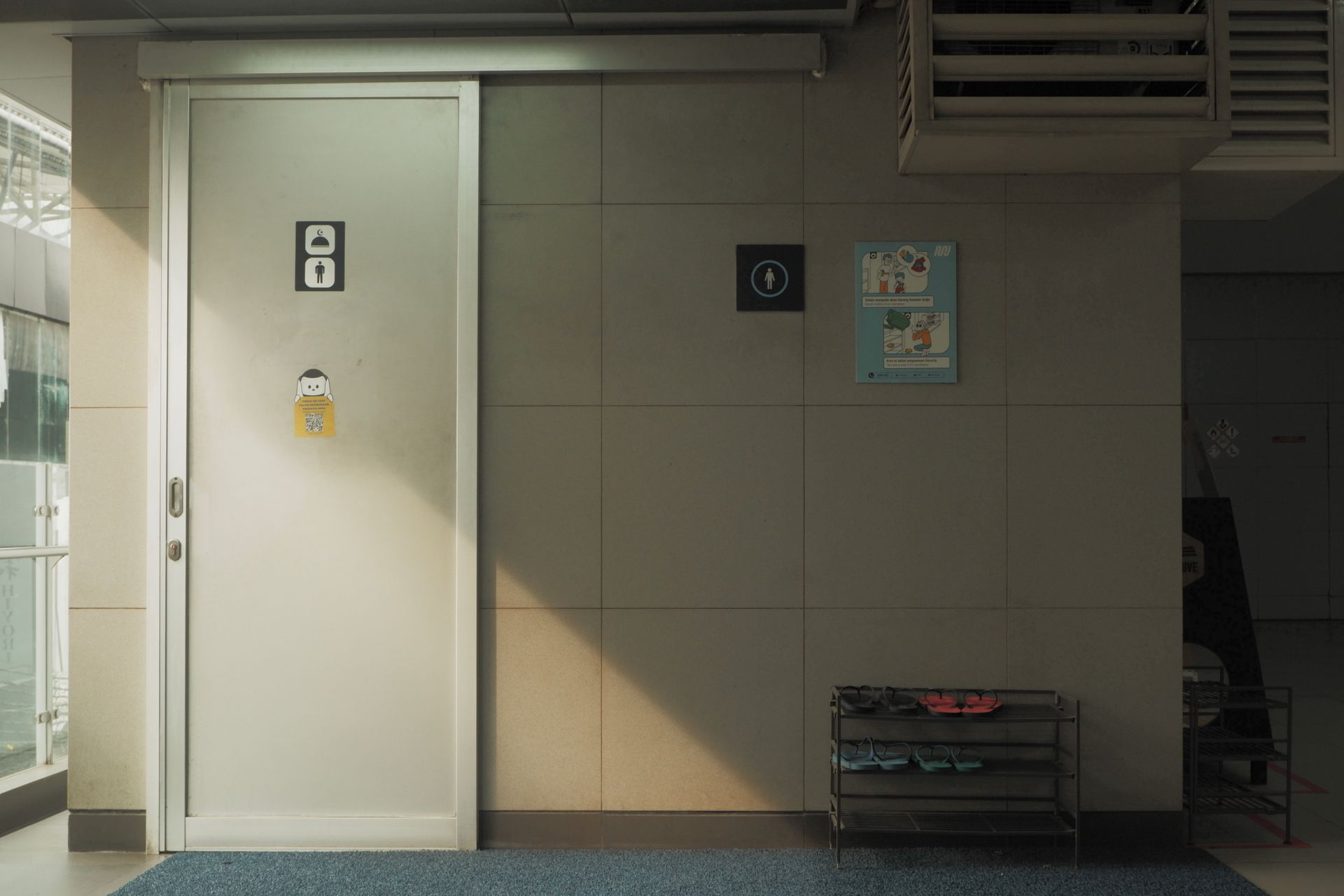 Entrance to a public restroom at a Jakarta MRT station, illuminated by morning light.