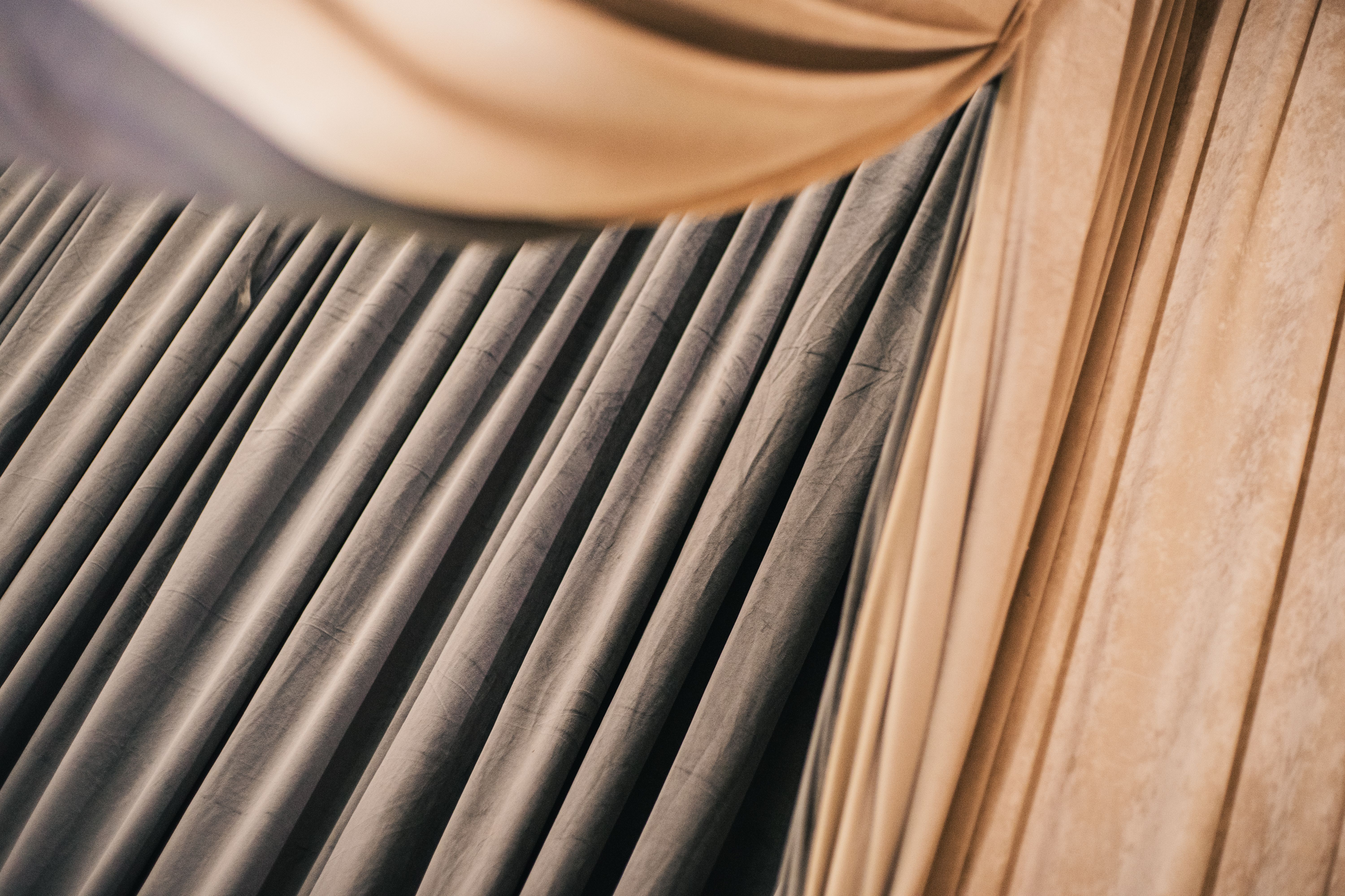 Abstract close-up of pleated beige and gray fabric drapes