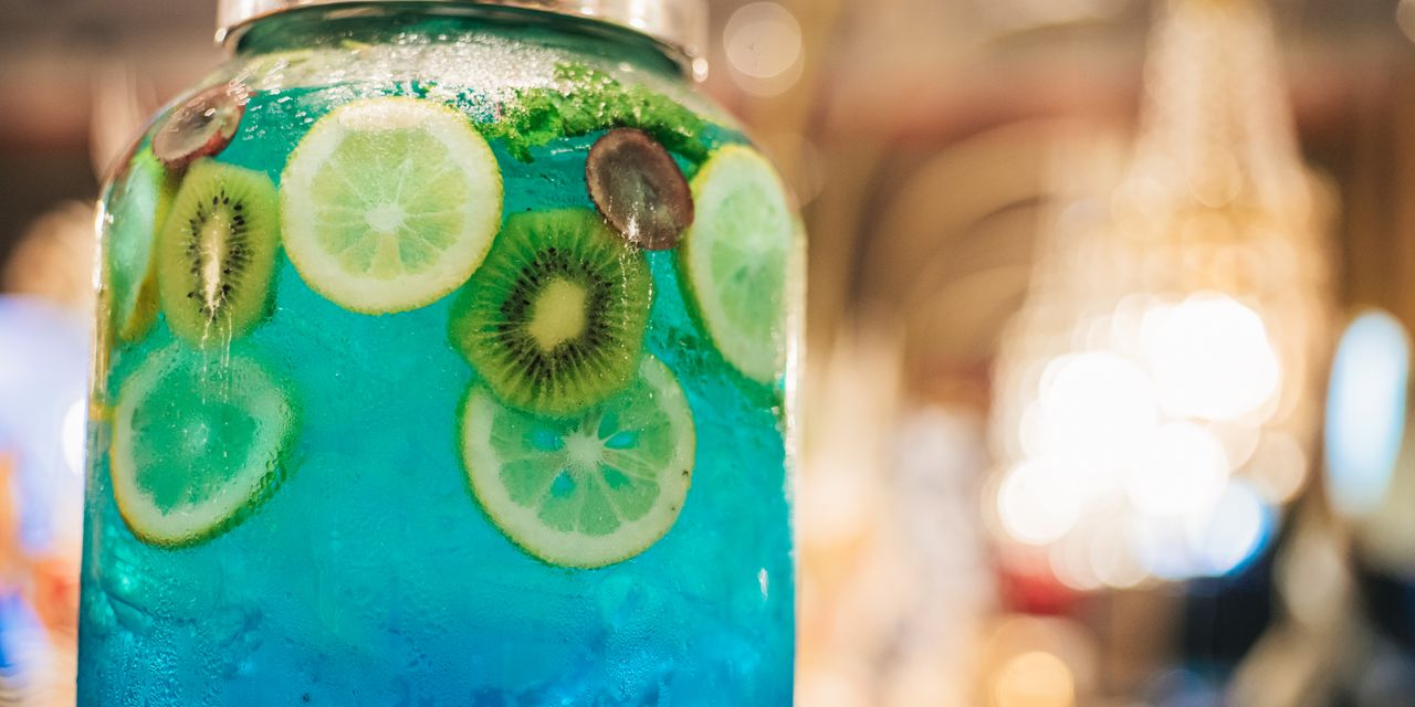Close-up of a vibrant blue drink in a glass jar with lemon and kiwi slices.