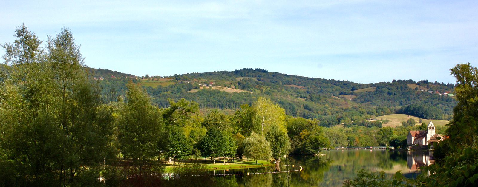 Explore the tranquil beauty of Beaulieu-sur-Dordogne with lush greenery and a serene river view.