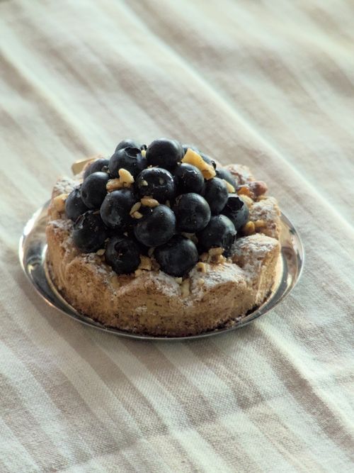 Free Appetizing blueberry tart with nuts on a silver plate, perfect for a dessert treat. Stock Photo