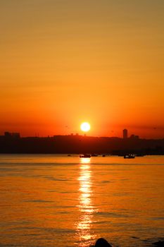 A breathtaking golden sunset over an urban waterfront, reflecting beautifully on the water.