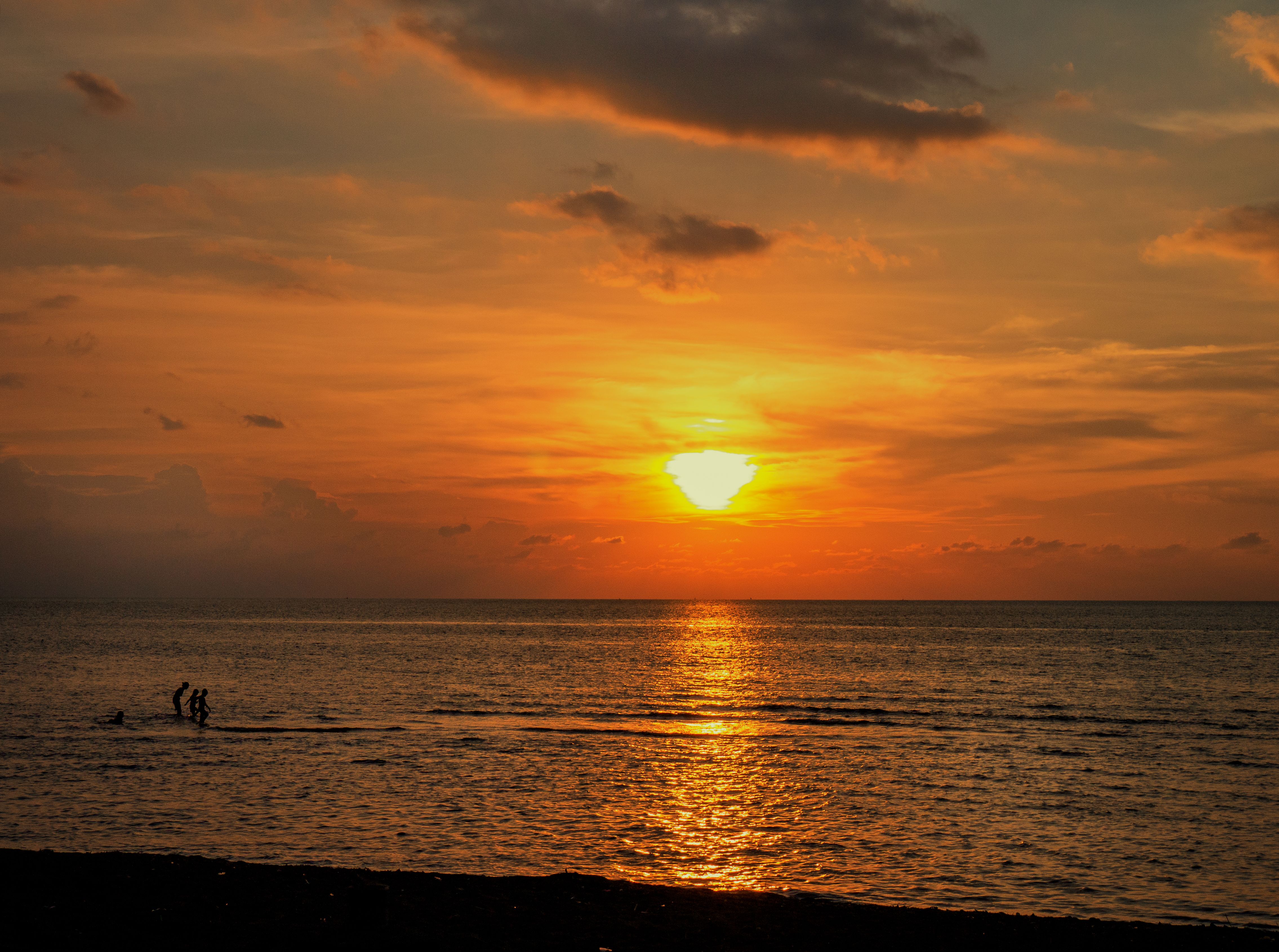Beautiful sunset over Bali's ocean with silhouettes of people against an orange sky. - Lovina - Bali