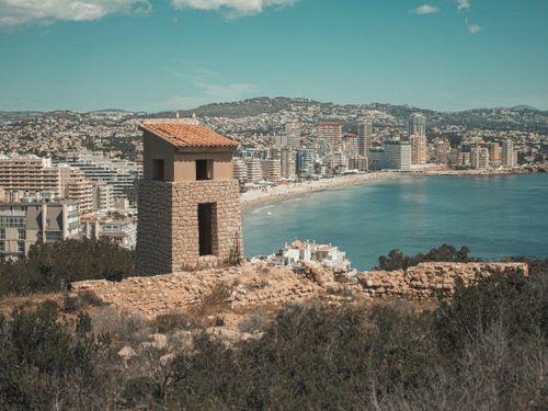 Free Scenic view of a Mediterranean city with coastline and historic tower under a blue sky. Stock Photo