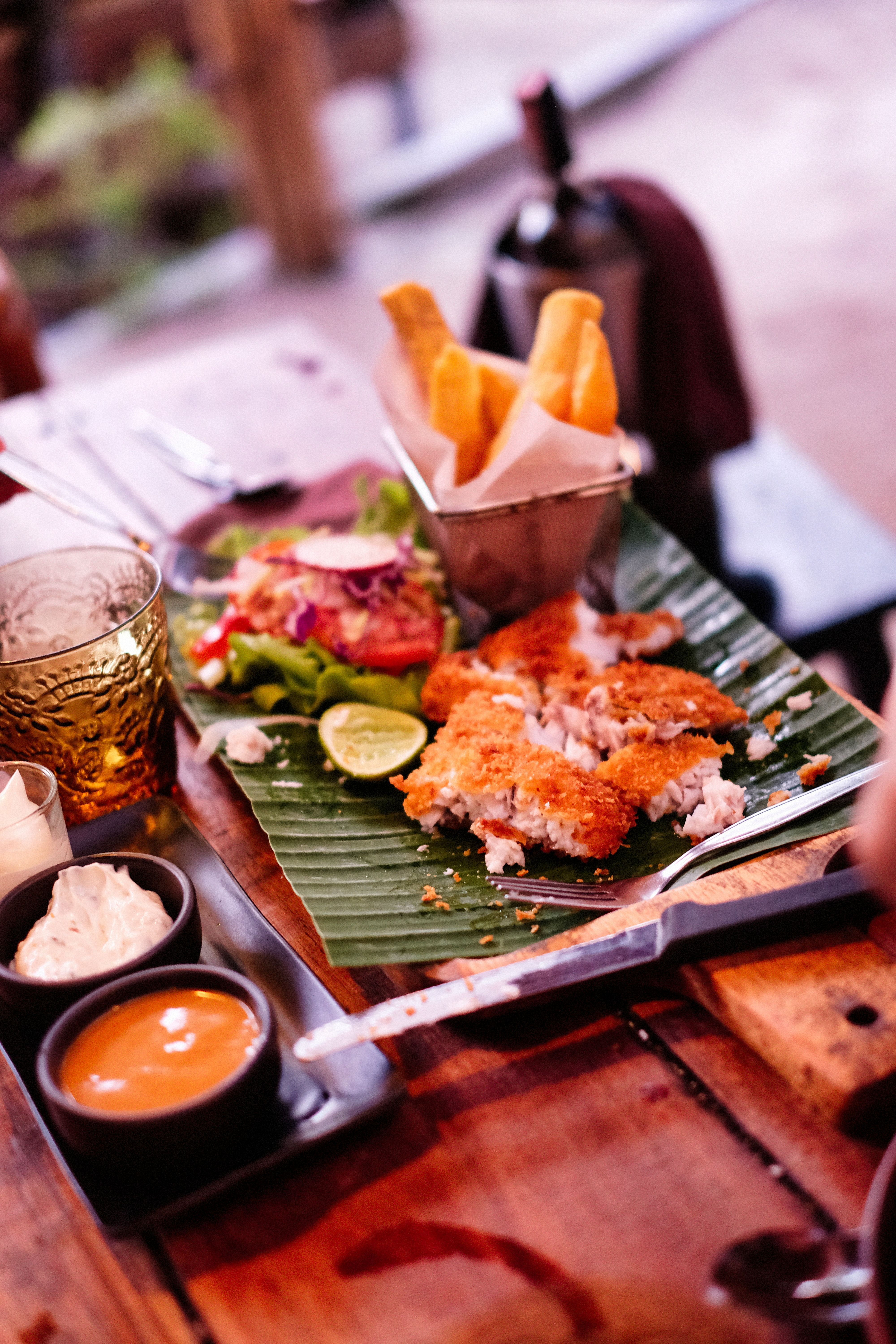 A basket of golden yuca fries with crisp, blistered edges and a soft interior, served with a bowl of garlic mojo dipping sauce.