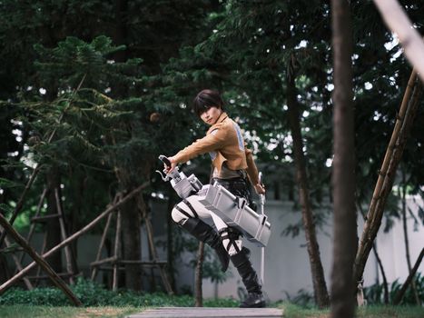 Person in detailed cosplay costume posing with gear in a lush forest setting.