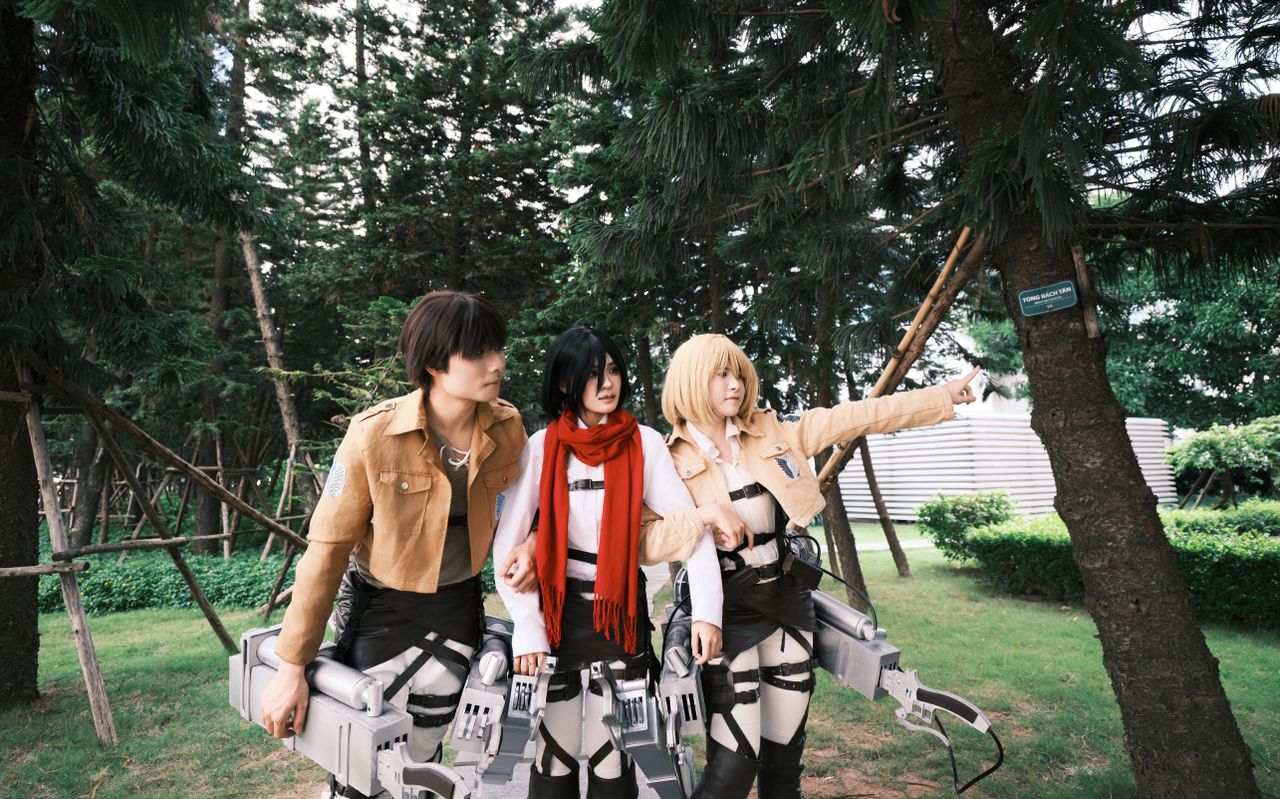 three anime cosplayers in action poses in a forest park setting