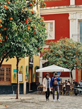 Vibrant street scene in Seville, featuring orange trees and a lively outdoor café setting.