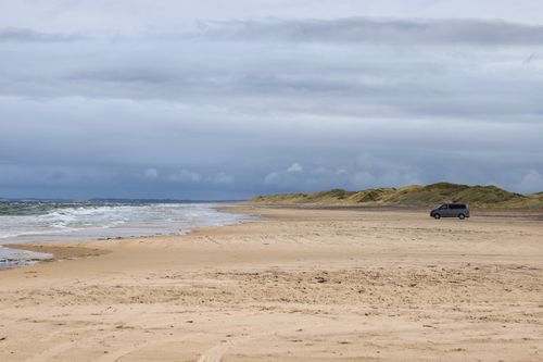 Free Solitary van on a sandy beach in Denmark under a cloudy sky. Stock Photo