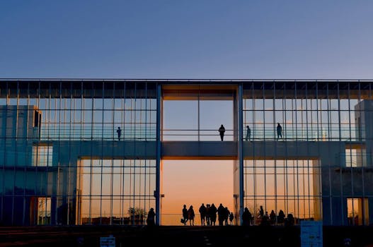 Silhouettes of people in a modern glass building during a scenic sunset in Japan.