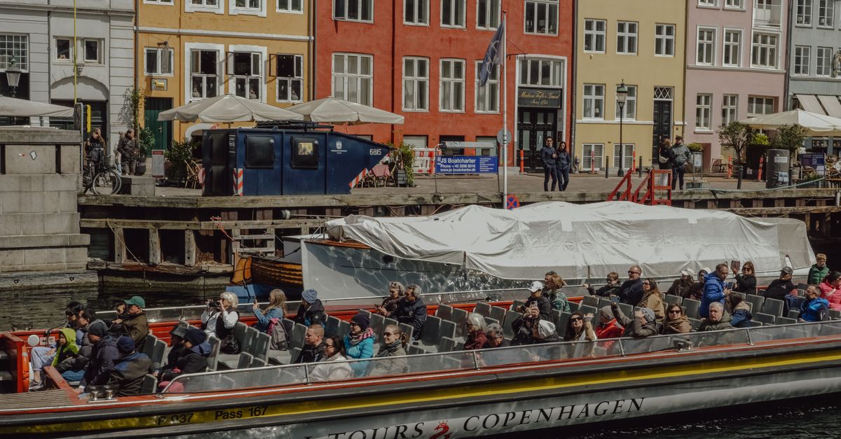 Tourists enjoying a scenic canal tour in Copenhagen, Denmark, with vibrant waterfront buildings.