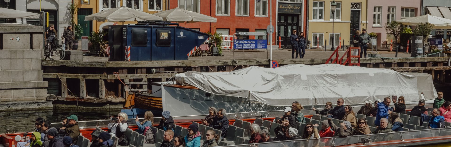 Tourists enjoying a scenic canal tour in Copenhagen, Denmark, with vibrant waterfront buildings.