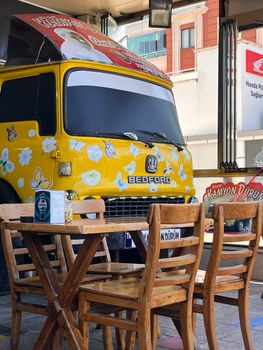 Vintage Bedford truck converted into a cafe with outdoor seating and colorful decor.