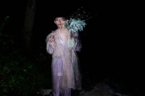 Free A night-time portrait of a man holding flowers, creating a dreamy effect. Stock Photo